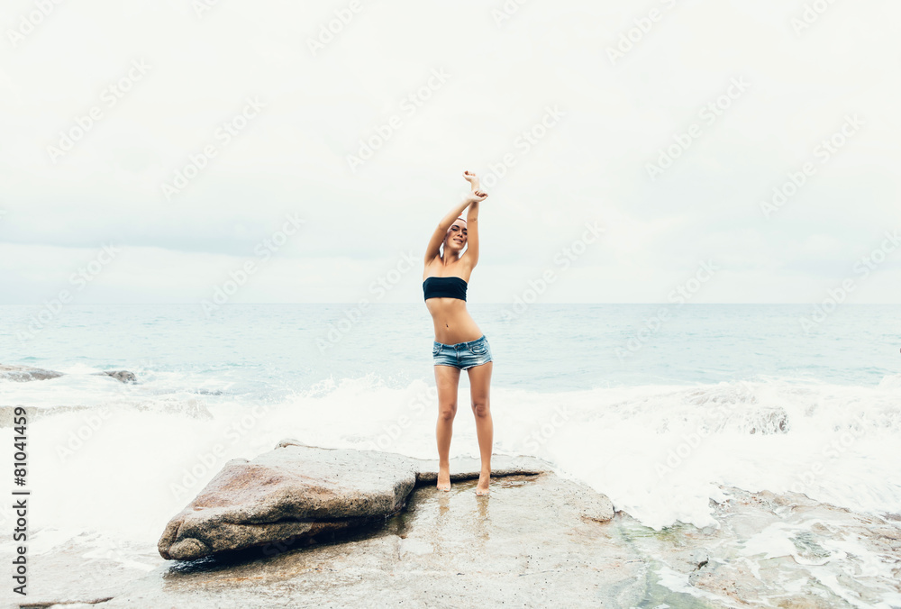 young woman having fun on a natural coastal rock high up