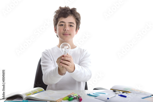 Caucasian smooth-skinned boy holds a lightbulb while doing homew photo