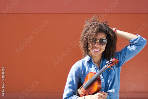 Smiling woman violinist with sunglasses and hand in hair