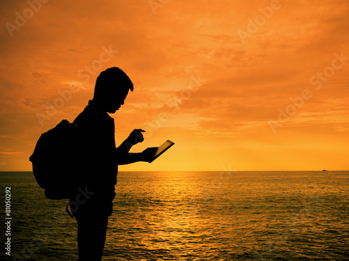 Silhouette man with digital tablet in hands at sunset beach
