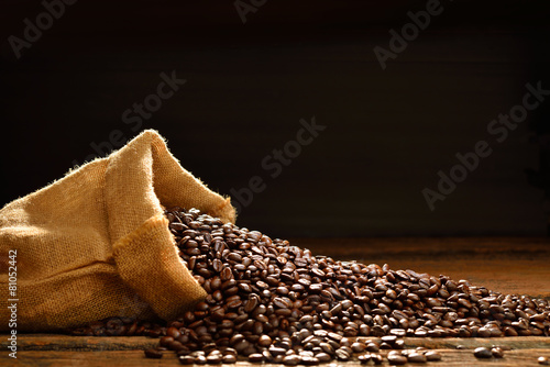 Coffee beans in burlap sack on wooden table