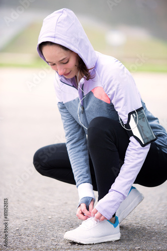 Young attractive woman tying shoelaces before a running session