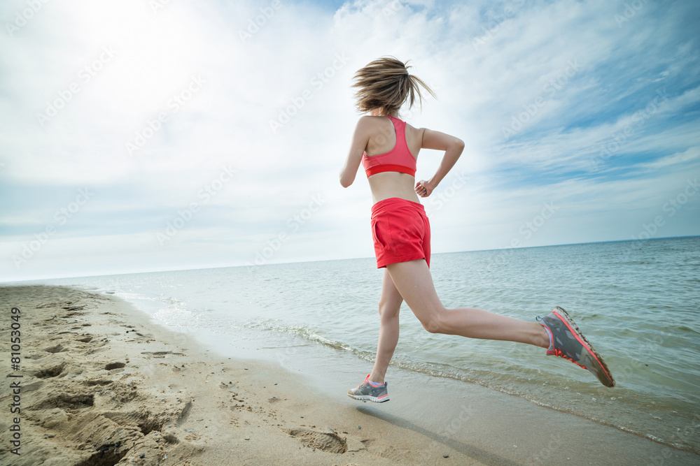 Young lady running at the sunny summer sand beach. Workout.  Jog
