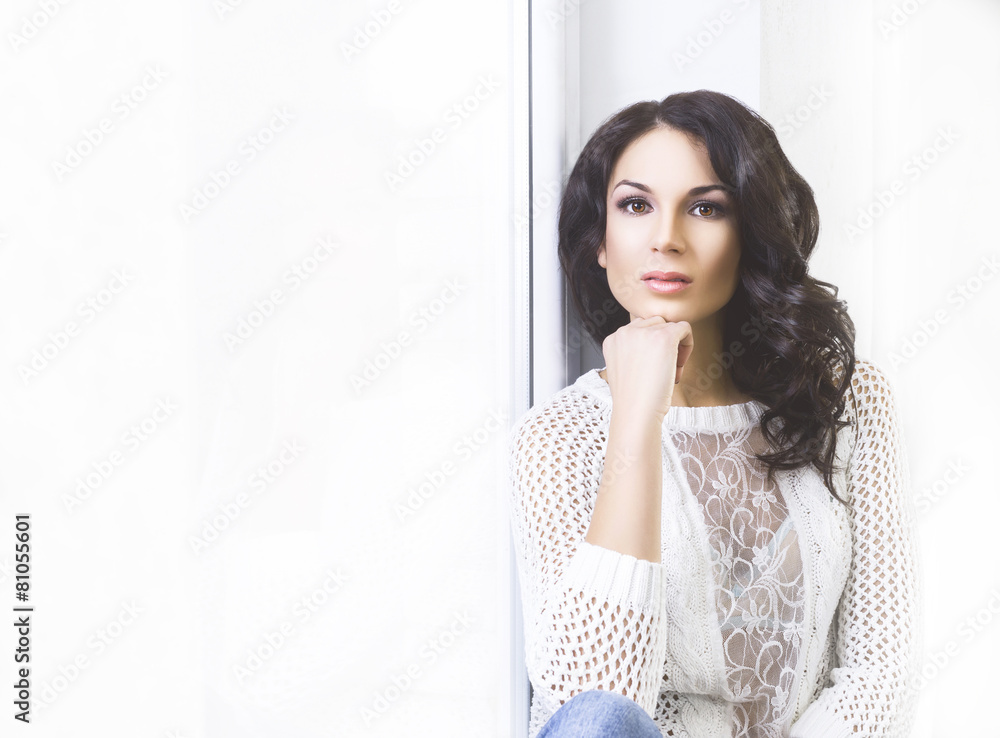 Young and beautiful brunette woman posing near the windowsill. D Young and beautiful brunette woman posing near the windowsill. D