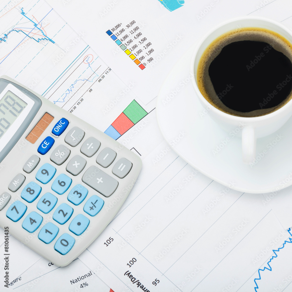 Coffee cup and calculator over market charts - close up shot Coffee cup and calculator over market charts - close up shot