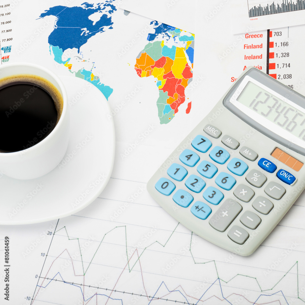 Coffee cup and calculator over map - close up shot Coffee cup and calculator over map - close up shot