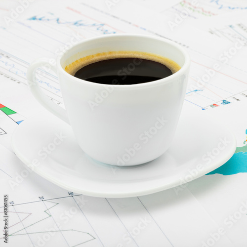 Coffee cup over some financial charts - close up shot