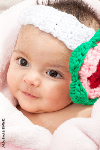 Hermosa bebita sonriente con una balaca adornada con una flor tejida photo