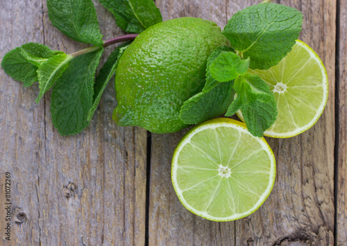 Juicy ripe limes and mint on wooden table