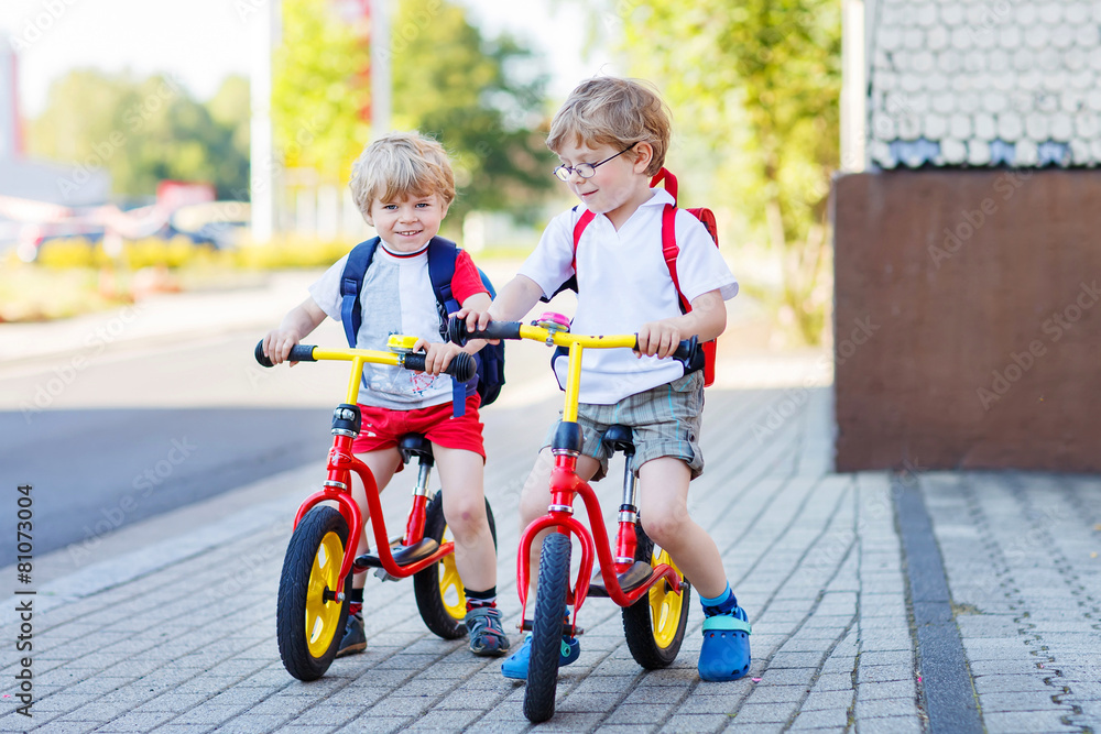 Two little siblings children having fun on bikes in city, outdoo Two little siblings children having fun on bikes in city, outdoo
