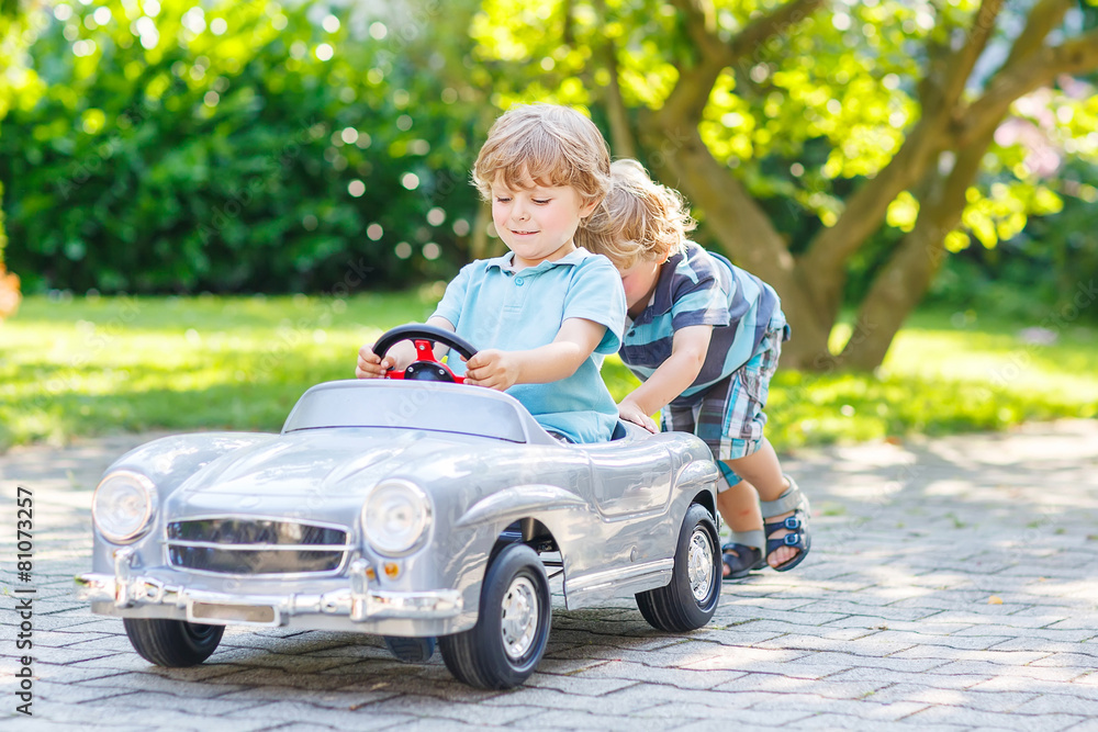 Two funny little friends playing with big old toy car