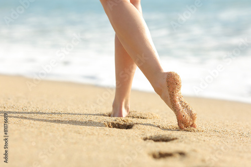 Woman legs and feet walking on the sand of the beach