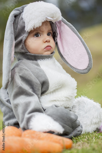Pequeña bebé de seis meses disfrazada de coneja junto a unas zanahorias
