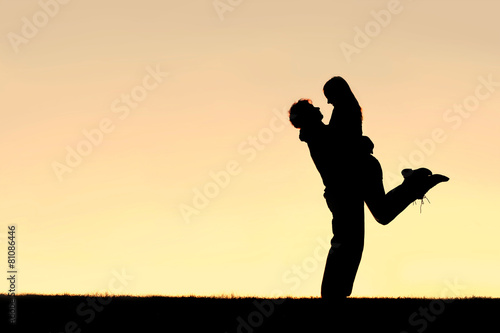 Silhouette of Happy Young Couple Hugging Outside at Sunset