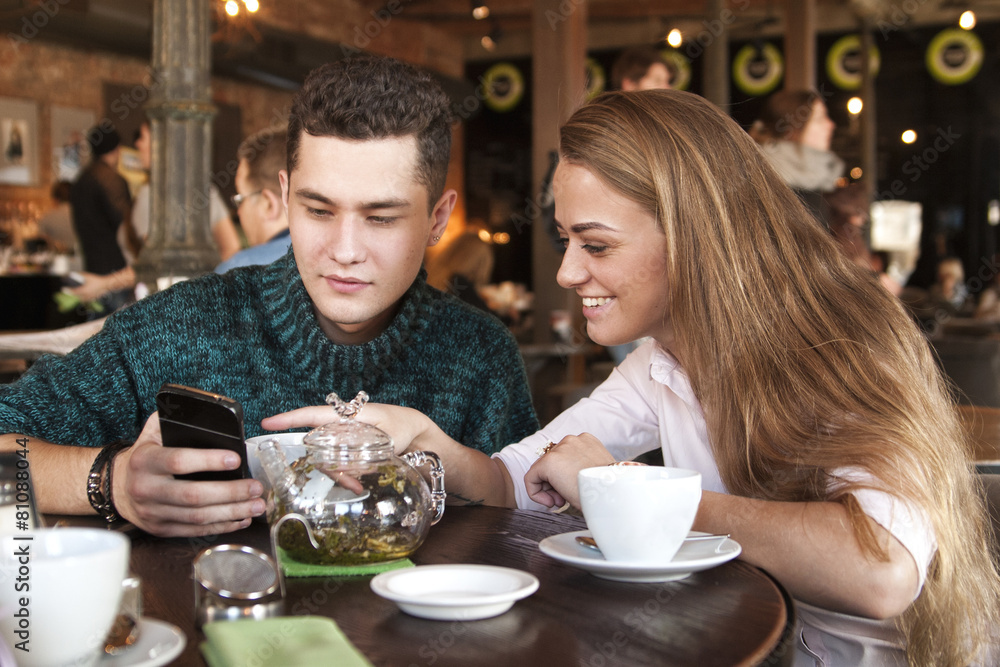 Young couple surfing the web looking at photos on mobile phone Young couple surfing the web looking at photos on mobile phone