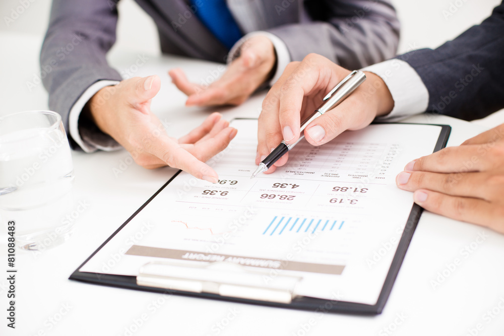 Two businessmen looking at report and having a discussion in off Two businessmen looking at report and having a discussion in off