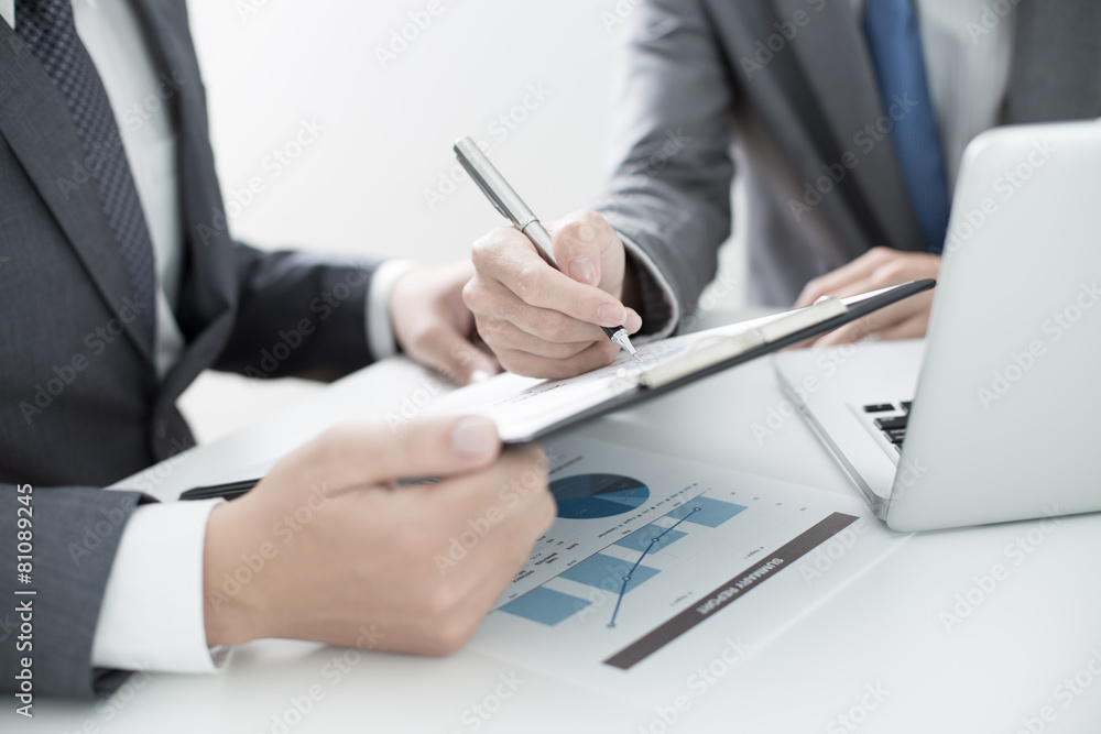 Two businessmen looking at report and having a discussion in off Two businessmen looking at report and having a discussion in off