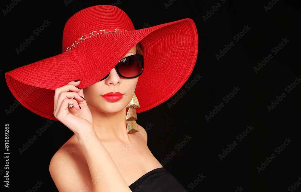 Woman in red hat and sunglasses over black background Woman in red hat and sunglasses over black background