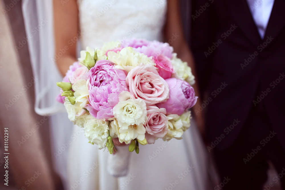 Bride holding a beautiful peonies and roses bouquet