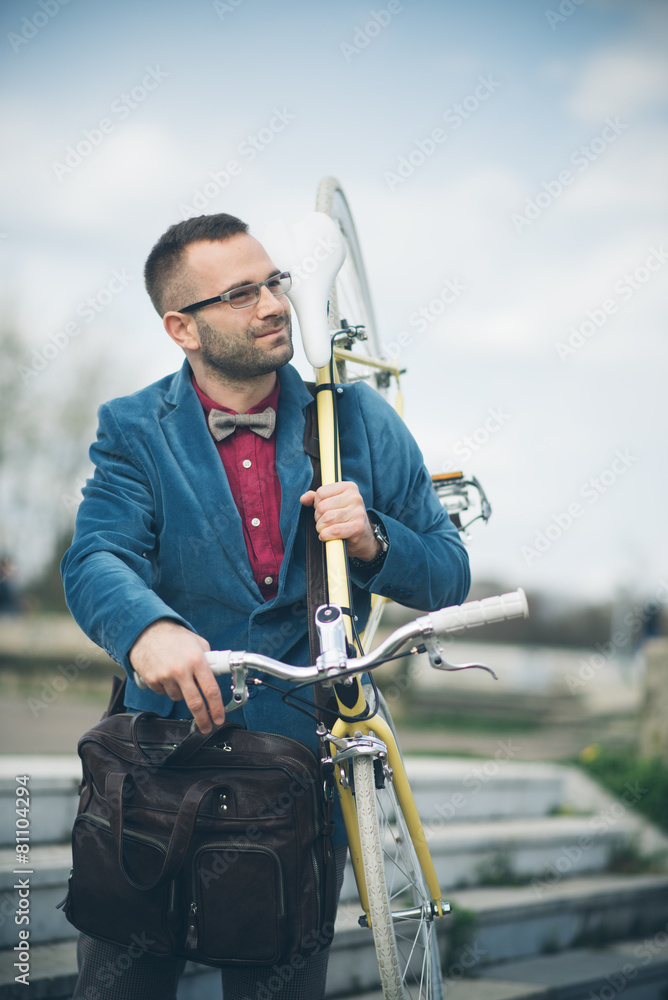 Young stylish man carrying fixedgear bicycle walking in the city