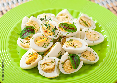Boiled quail eggs halves on a green plate