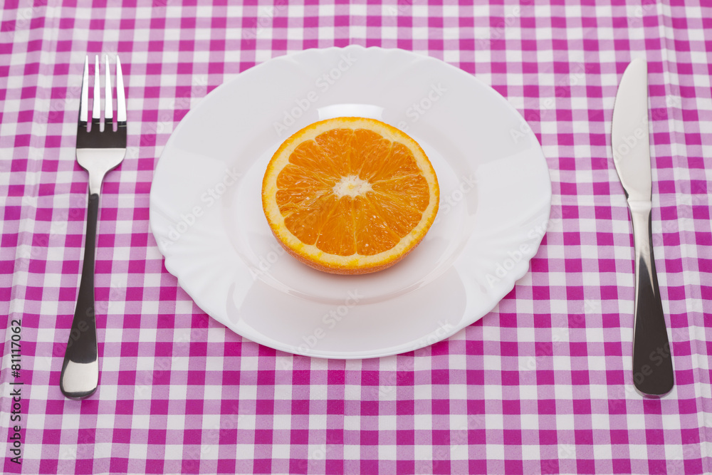orange fruit in a white ceramic plate with the fork and knife orange fruit in a white ceramic plate with the fork and knife