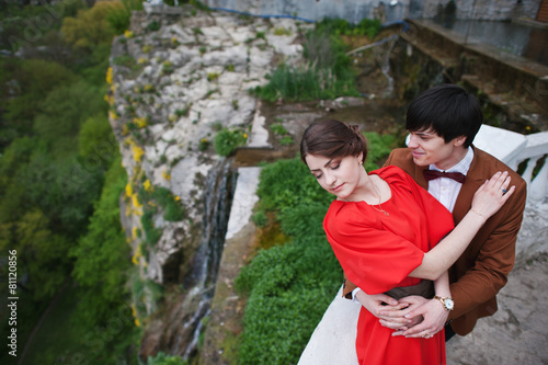 Young beautiful couple kiss near waterfall