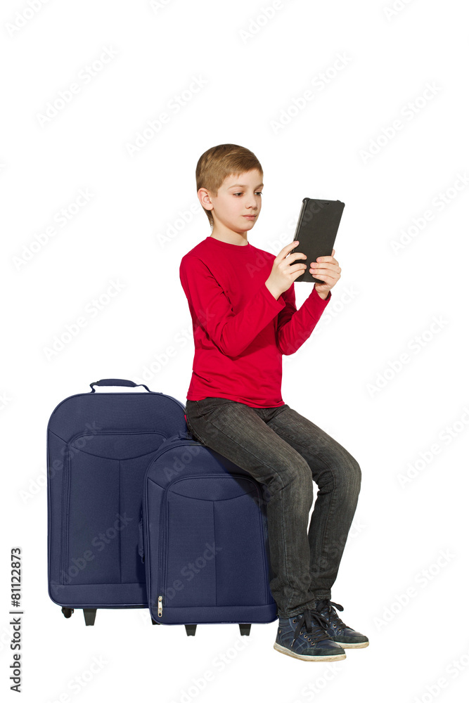 Boy sitting on travel bags using tablet isolated on white Boy sitting on travel bags using tablet isolated on white