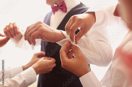 Hands helping the groom with buttons