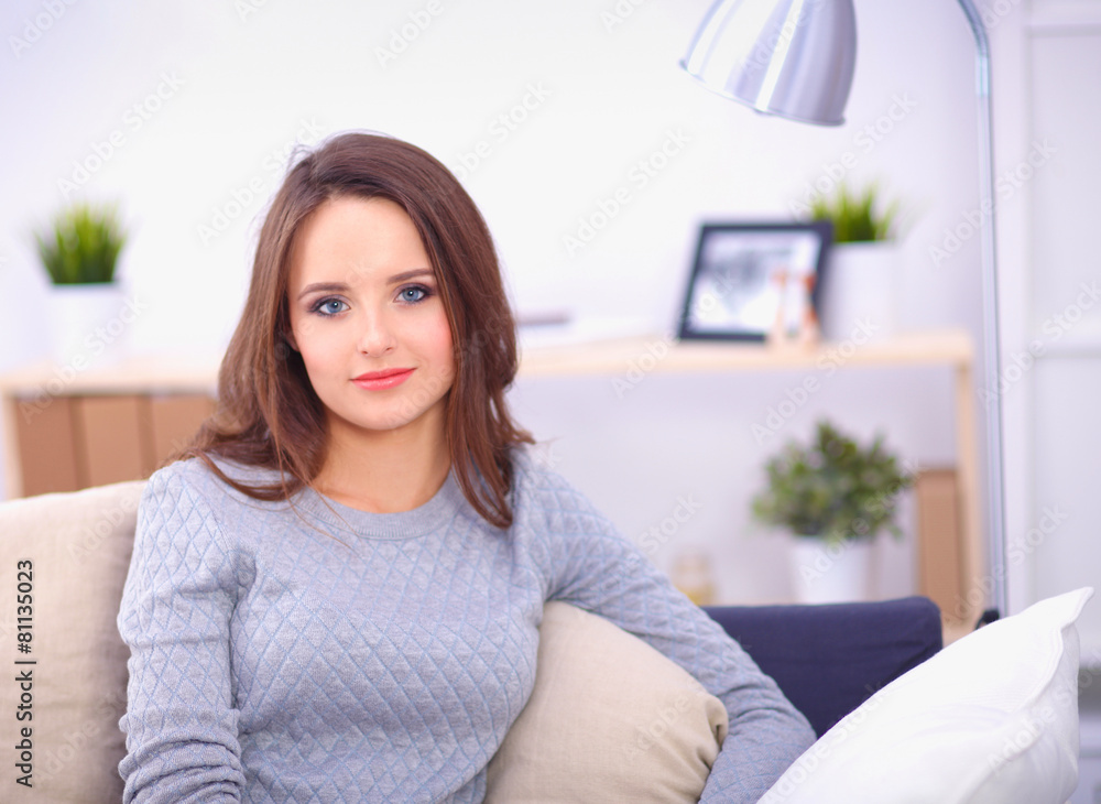 Portrait of happy young woman sitting on sofa Portrait of happy young woman sitting on sofa