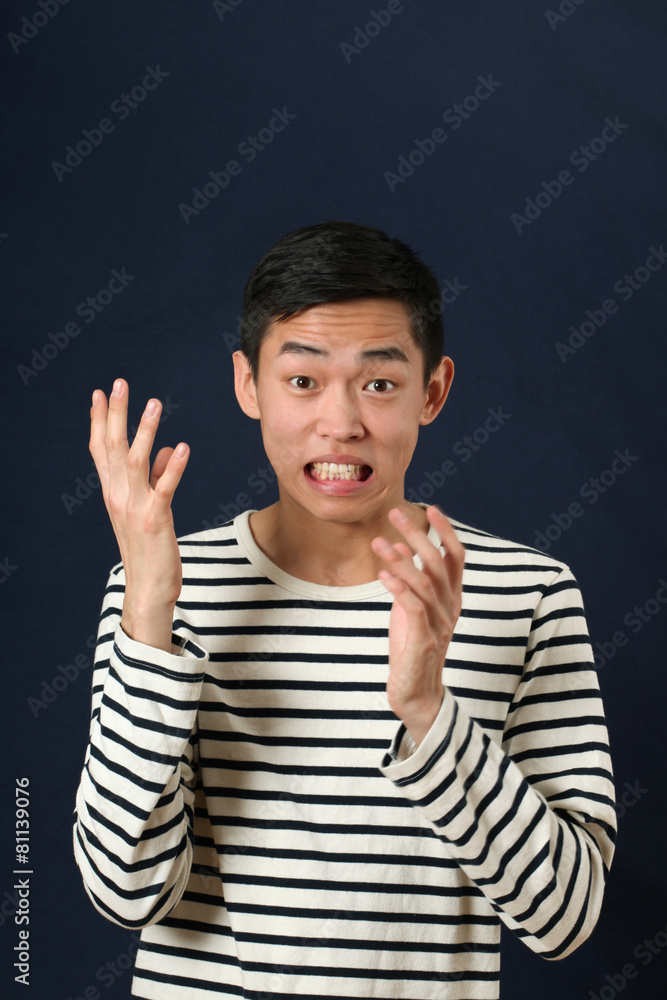 Displeased young Asian man gesturing with two hands and looking Displeased young Asian man gesturing with two hands and looking