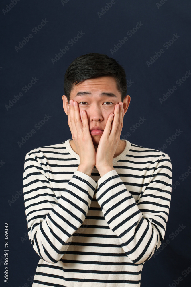 Disappointed young Asian man covering his face by palms and look Disappointed young Asian man covering his face by palms and look