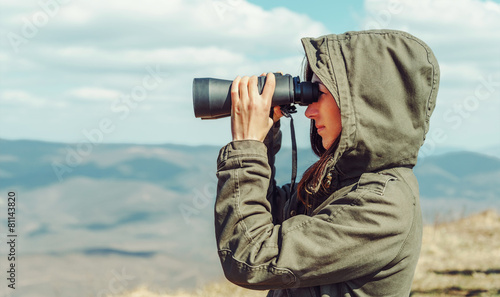 Hiker looking in binoculars in the mountains