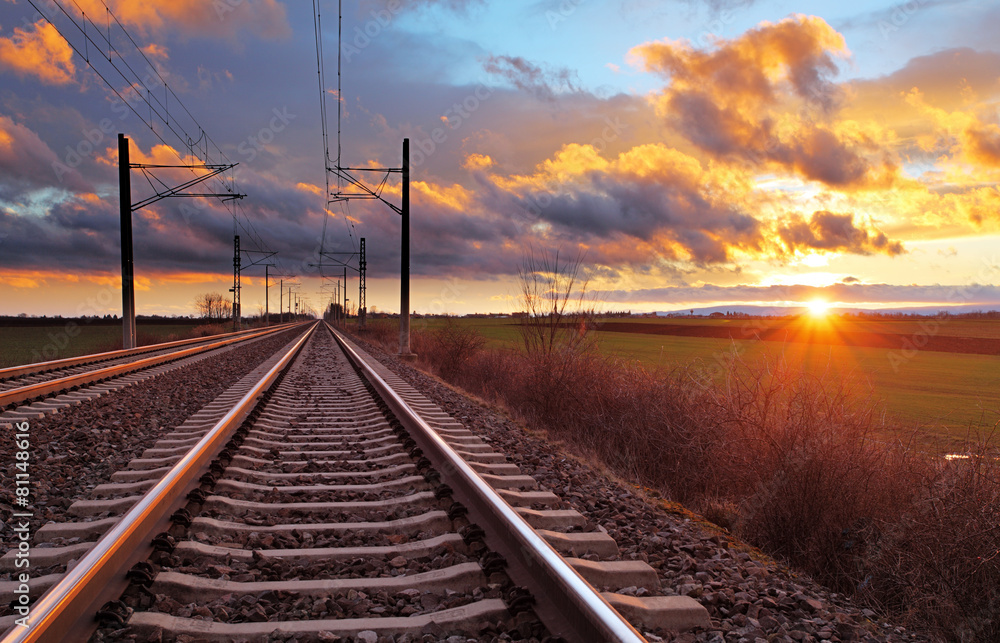 Naklejka premium Pomarańczowy zachód słońca w niskich chmurach nad kolejowych
