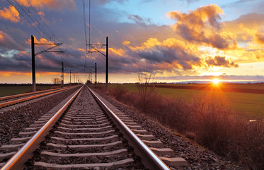 Fotobehang Trein Oranje zonsondergang boven spoorlijn  © TTstudio