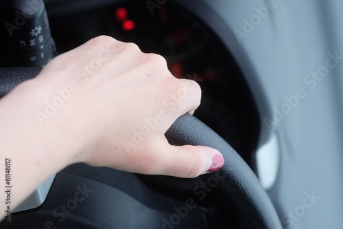 Hand of a woman behind the wheel of car