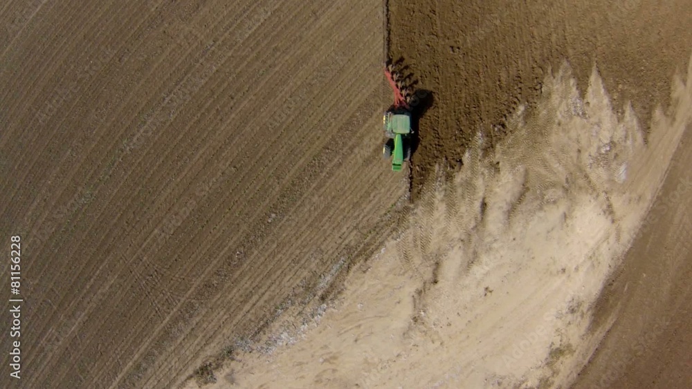 aerial view tractor cuts furrows in farm field for sowing farm tractor with rotary harrow plow preparing land for sowing. aerial view tractor cuts furrows in farm field for sowing farm tractor with rotary harrow plow preparing land for sowing.