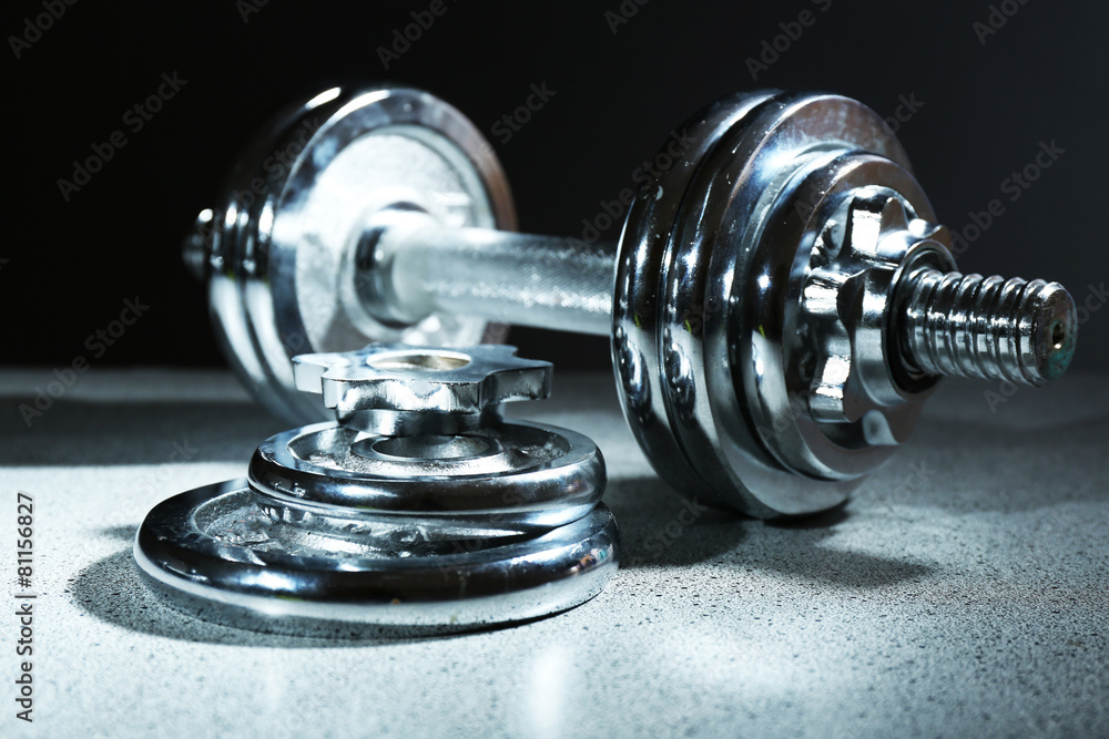 Dumbbell on floor, on dark background Dumbbell on floor, on dark background