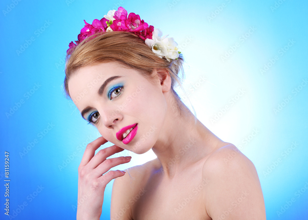 Portrait of young woman with flowers in hair on blue background Portrait of young woman with flowers in hair on blue background