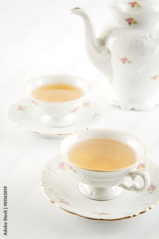 Old-style kettle with two cups of tea on white background