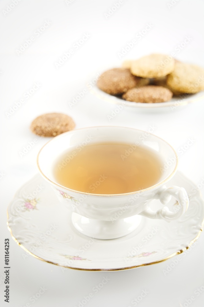 Old-style studio shot of cups of tea with cookies on white Old-style studio shot of cups of tea with cookies on white