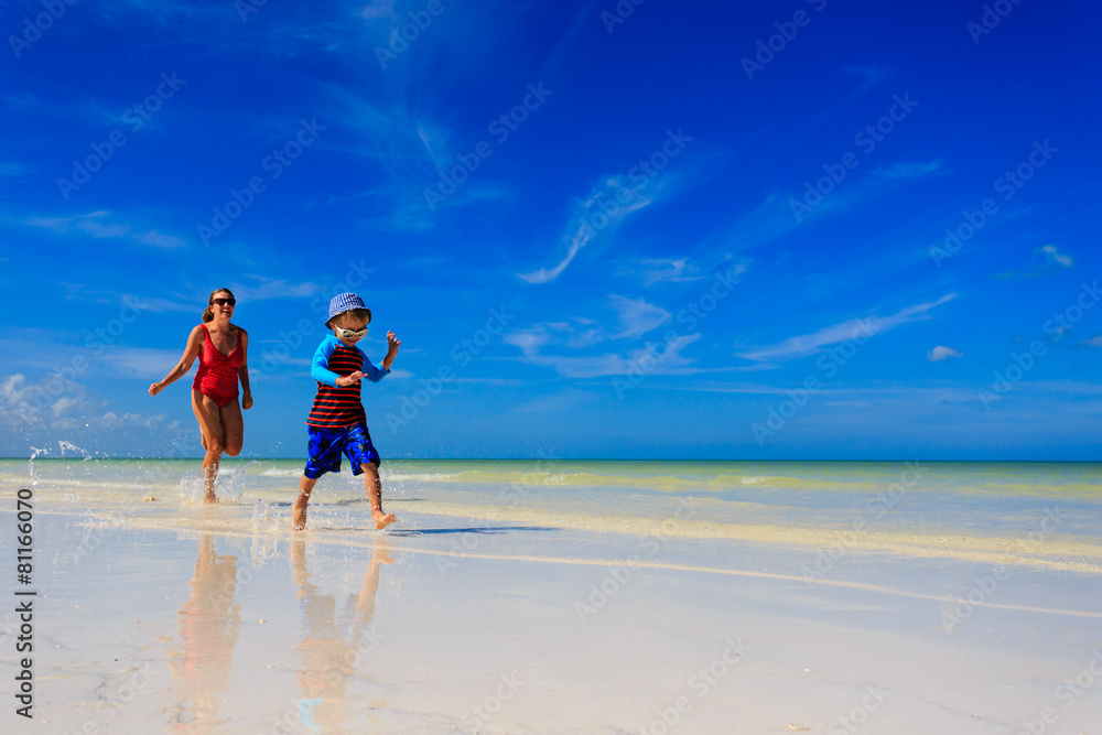 mother and son running in water on the beach mother and son running in water on the beach