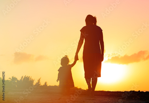 mother and little daughter walking at sunset