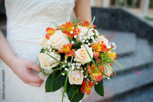 Bride is holding a beautiful wedding bouquet of roses