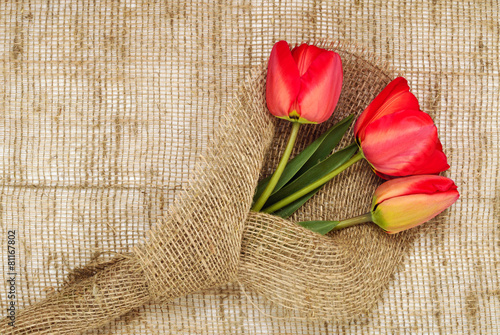 Fototapeta Naklejka Na Ścianę i Meble -  bouquet of red tulips on burlap background