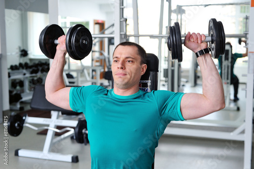 Man lifting dumbbells in a fitness club