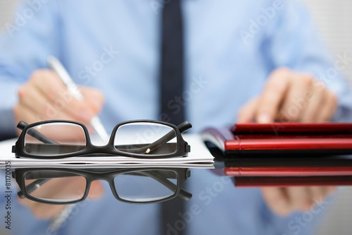 blurred businessman is working in office , focus is on eyeglasse