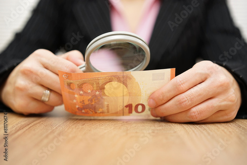 Businesswoman looking through a magnifying glass money. fraud co