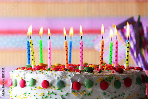 Birthday cake with candle on colorful striped background