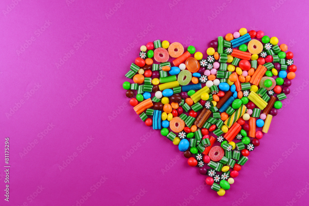 Colorful candies in heart shape on purple background Colorful candies in heart shape on purple background